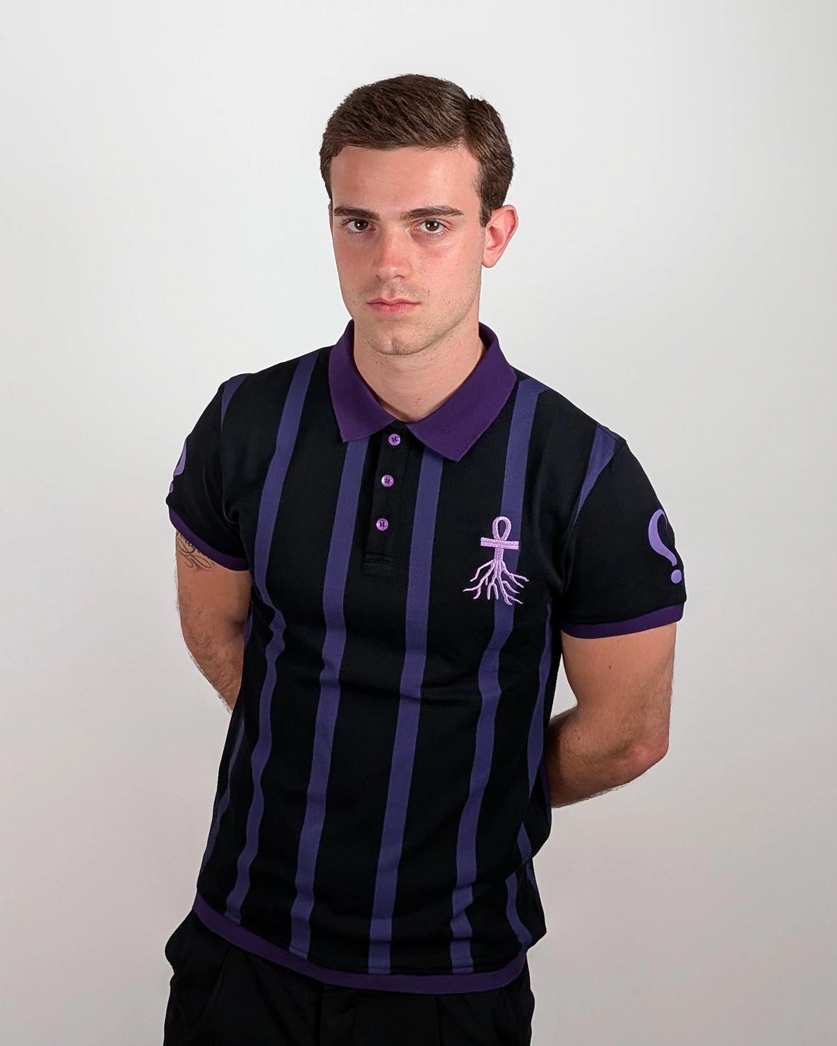 Model wearing WESSENCE ENIGMA vertical striped polo, full front view, dark streetwear look.