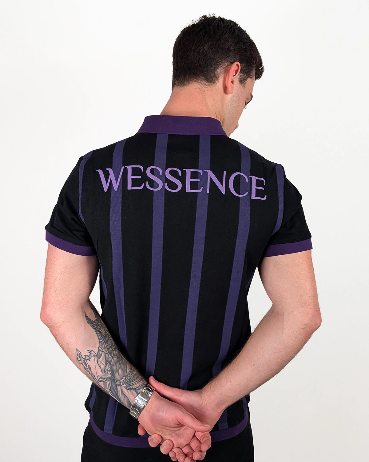 Back view WESSENCE ENIGMA striped polo on model, violet stripes and logo details, men's urban outfit.