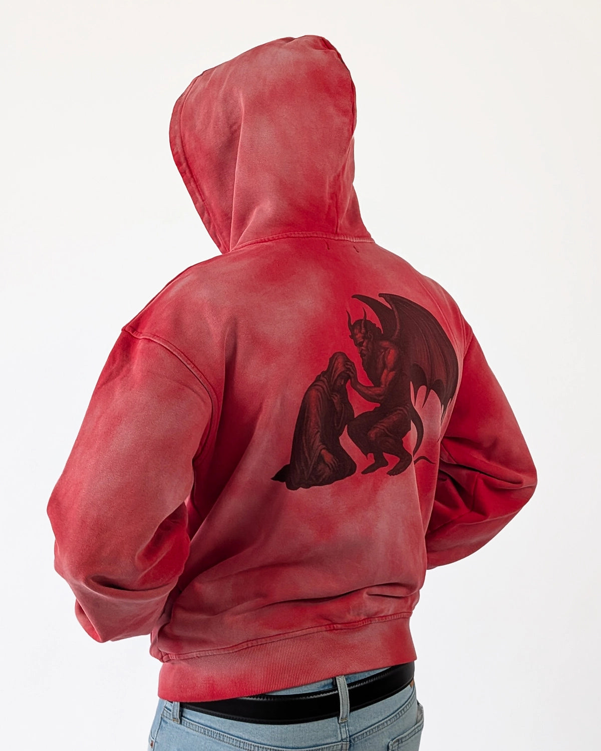 Model wearing WESSENCE HELL TEMPTATION red washed hoodie, partial side back view, premium streetwear.