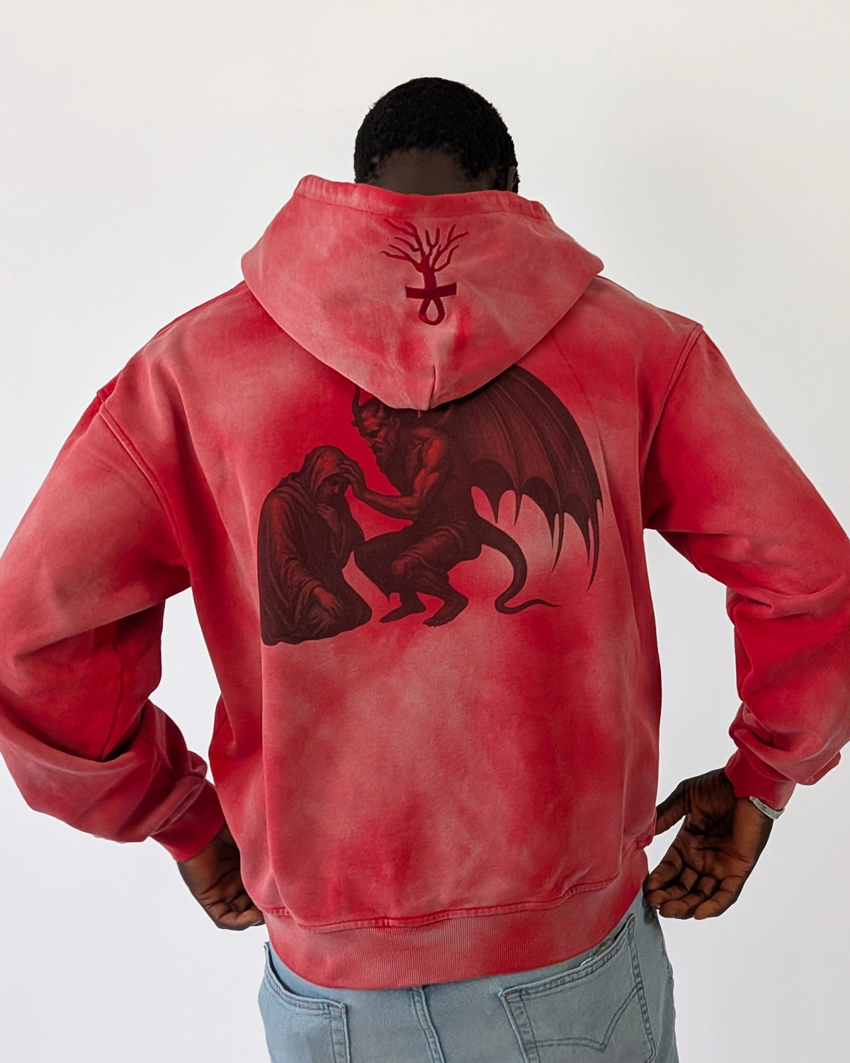 Model wearing WESSENCE HELL TEMPTATION red washed hoodie, full back view, large black winged demon graphic.